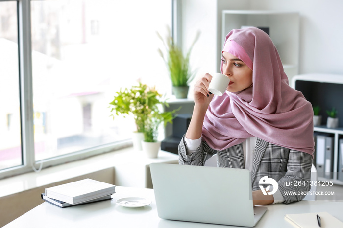 Muslim woman working on laptop in office