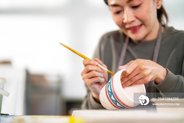 亚洲女性在家学习彩绘自制陶器。自信女性喜欢爱好a