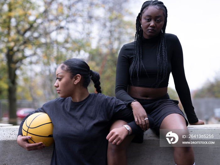 Two female friends outdoors holding basketball ball