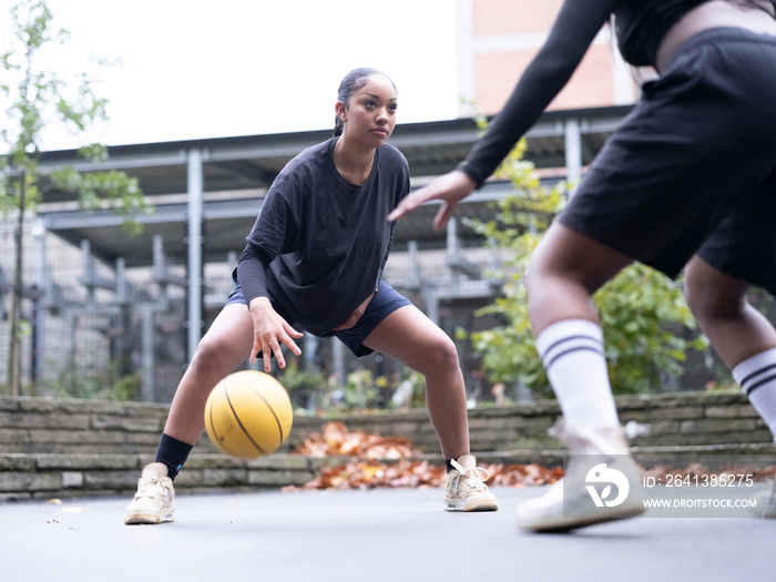 Two female friends playing basketball outdoors