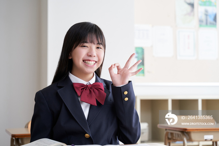 教室でOKポーズをする日本人女子中学生