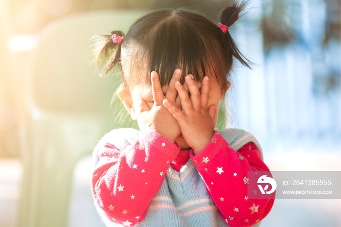 Cute asian baby girl closing her face and playing peekaboo or hide and seek with fun