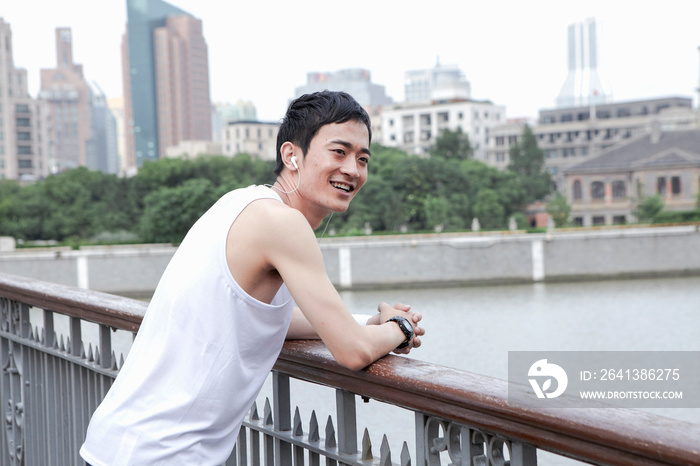 Male jogger taking a break on bridge