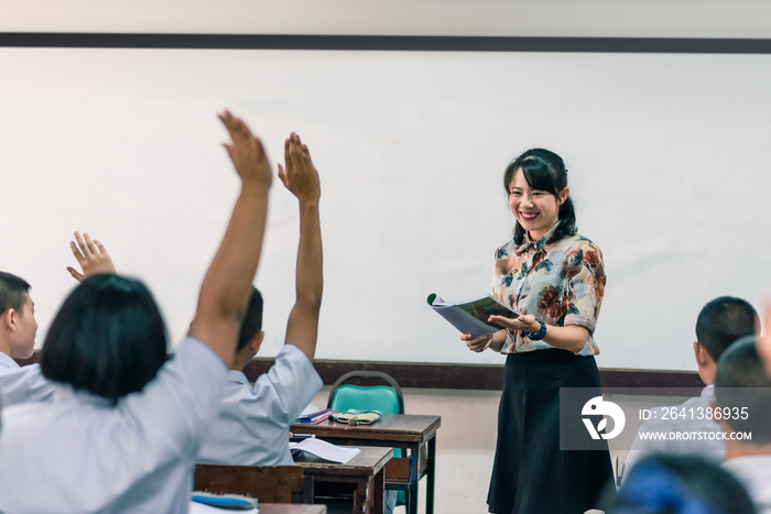 一位面带微笑的亚洲女高中老师在课堂上用as教穿白色制服的学生