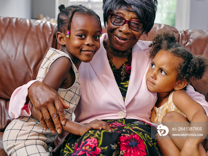 Portrait of great grandmother sitting on sofa with great granddaughters