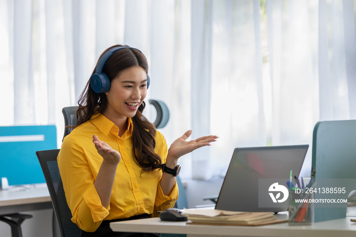 快乐的年轻亚洲商业女性戴着耳机与她的企业进行在线视频电话会议