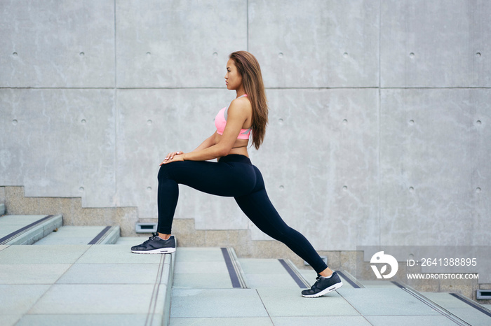 Young woman exercising stretching legs on city stairway