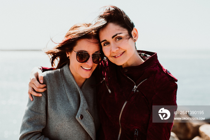 .Lesbian couple laughing together on their trip to Porto in Portugal. Walking along the coast on a w