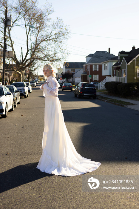 fashion portrait of non-binary person wearing white dress in suburbia