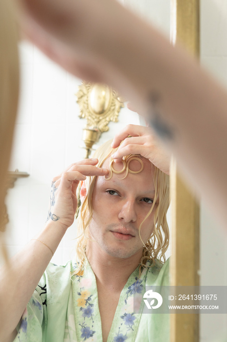 non-binary hispanic person doing intricate hair style in the mirror