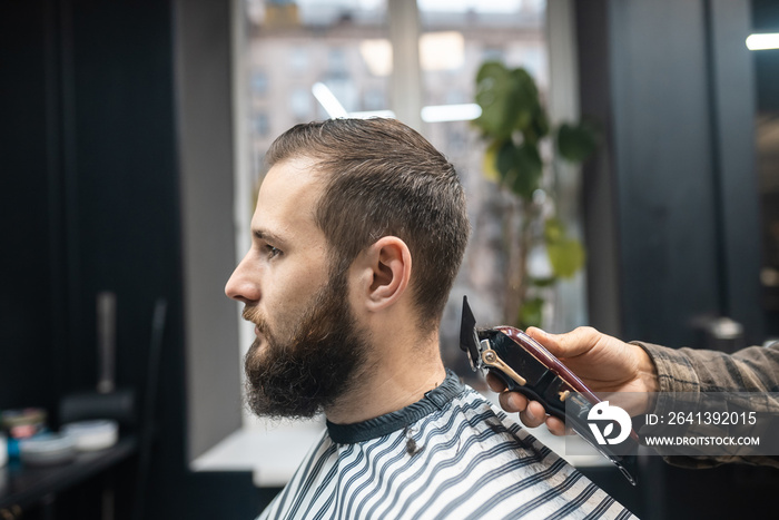 Master in barbershop makes mens haircutting with hair clipper