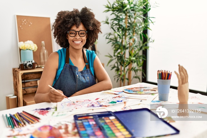 美丽的非洲裔美国女人，留着非洲头发，带着快乐而酷的微笑在艺术工作室画画o