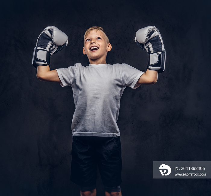 Cheerful handsome little boy boxer with blonde hair dressed in a white t-shirt wearing boxing gloves