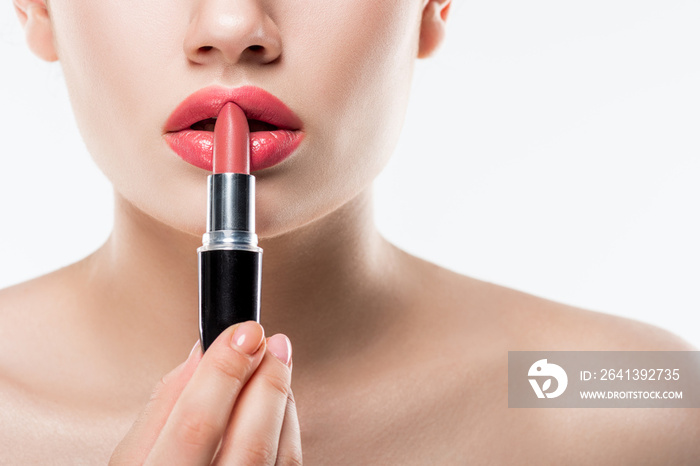 cropped view of young woman applying pink lipstick, studio shot isolated on white