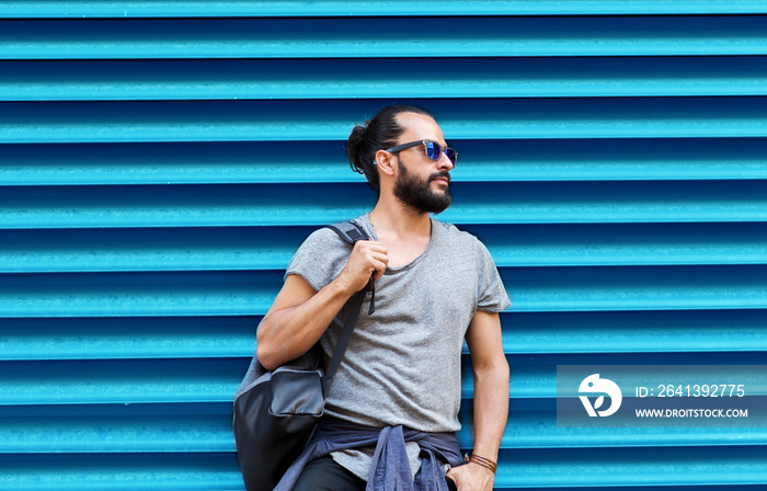 man in sunglasses with bag standing at street wall