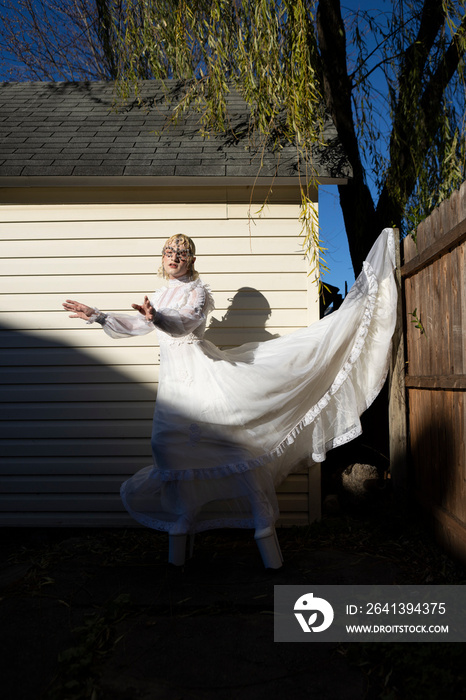 fashion portrait of non-binary person wearing white dress in dramatic sunlight