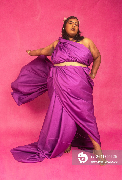 Malaysian Indian individual posed against pink background, styled in pionk and white, studio setting