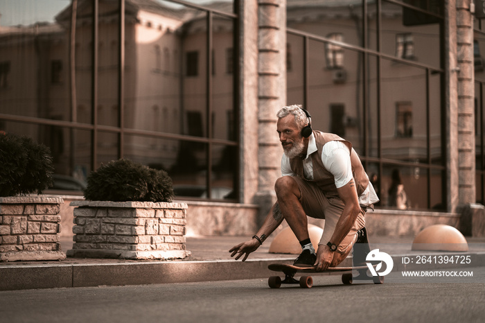 Adult bearded man portrait with longboard. Stylish model in casual clothes ride skateboard on city s