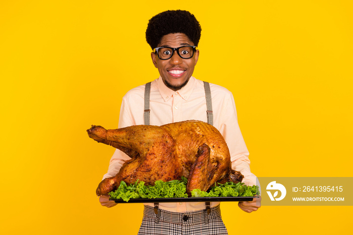 Photo portrait man in glasses keeping baked chicken on thanksgiving day smiling isolated bright yell