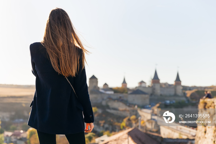 girl back to camera looking at a medieval fortress. fortress wit