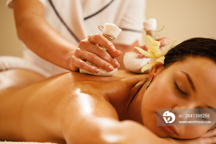 Close-up of woman receiving Thai herbal compress massage at the spa.