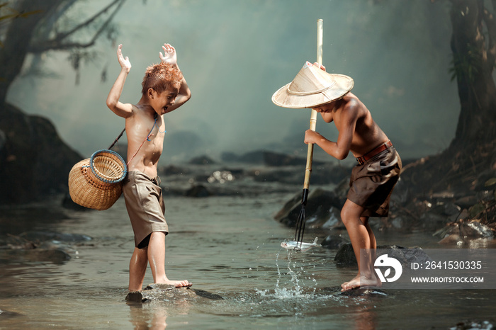 Two boys Fishing in the streams near their home in the countryside of Thailand