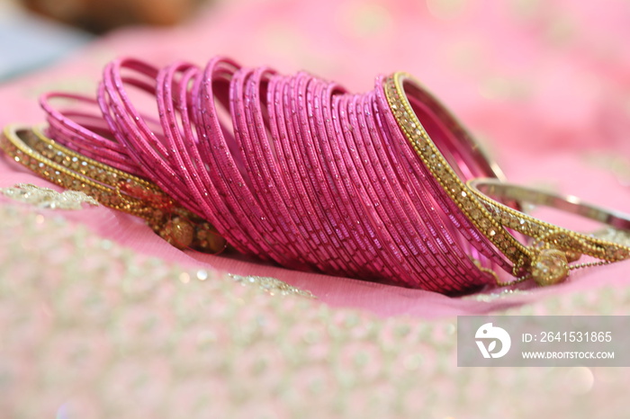 dozens of pink glass decorative bangles spread on pink lehenga