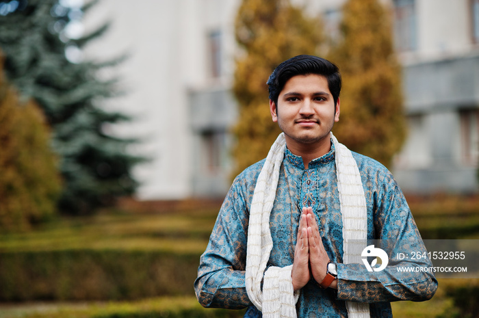 Indian man wear on traditional clothes with white scarf posed outdoor against green bushes at park, 