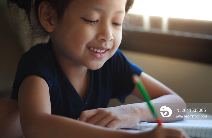 Child girl writing on the book with smile.Selective Focus