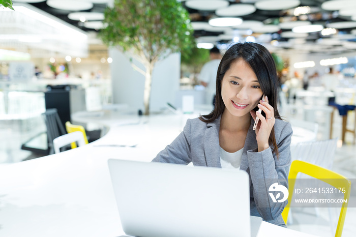 Businesswoman working on laptop computer and talk to mobile phone