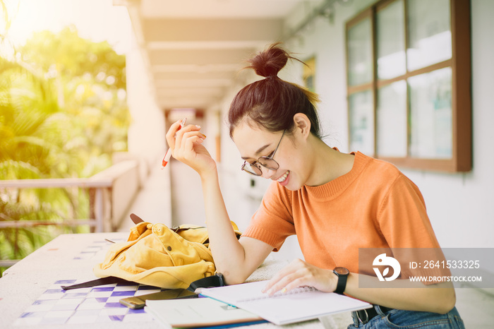 一个年轻的女人或亚洲大学生少女微笑着坐着，一边记着不