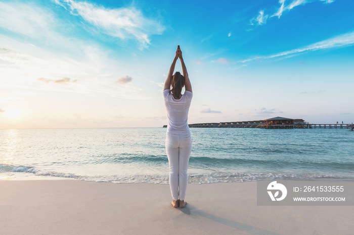 Asian woman practicing yoga Lotus pose on the beach in Maldives at sunset,Feeling so comfortable and