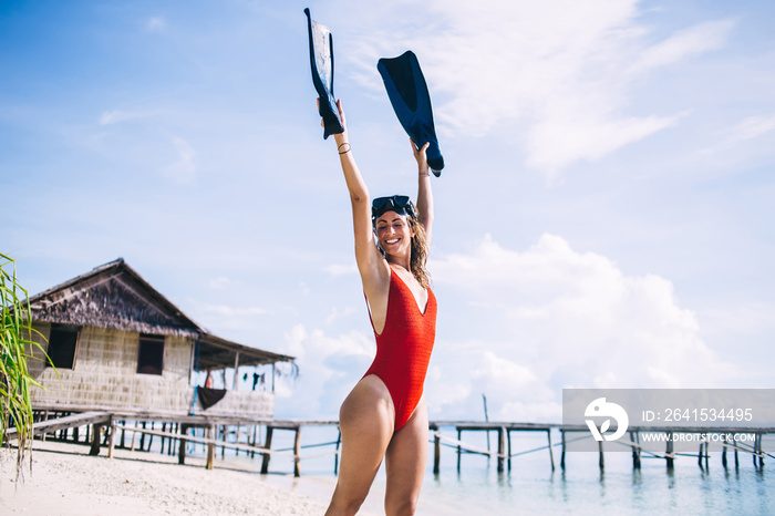 快乐的女人在巴哈马热带岛屿的海岸线上，一边养着脚蹼一边满足
