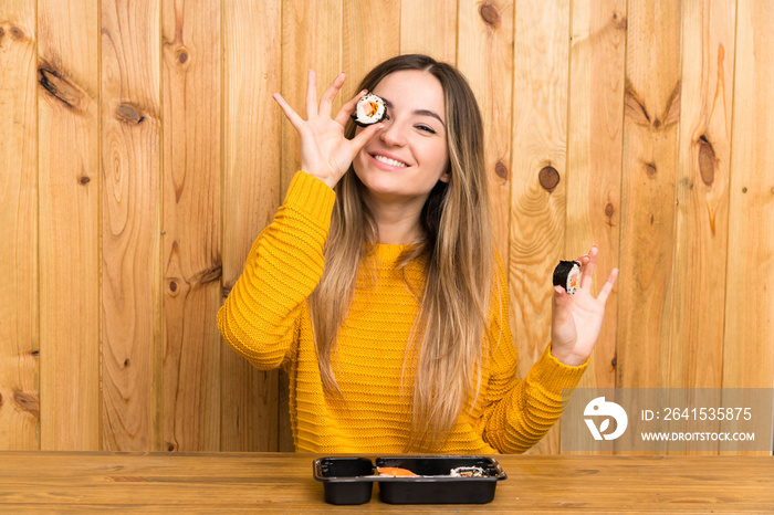 Young woman with sushi over wood background