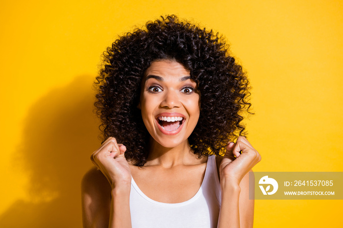 Photo of astonished dark skin girl fists up open mouth smile celebrate isolated on yellow color back