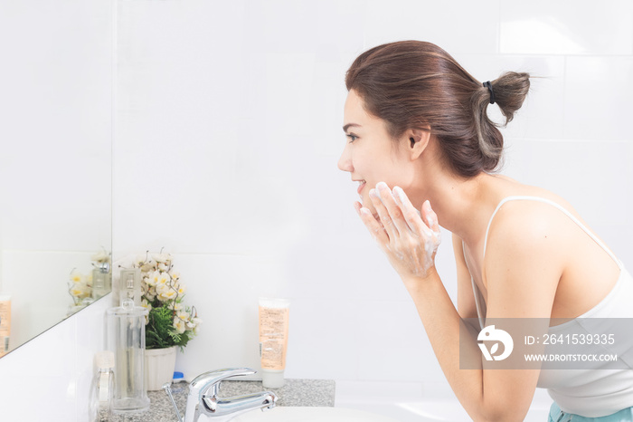 Asian woman wash her face in the bathroom before shower.