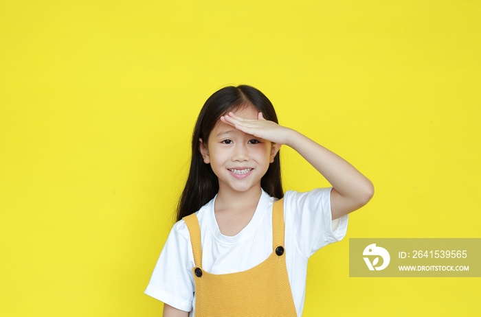 Attractive little child girl shielding her eyes by hand on forehead isolated on yellow background. P