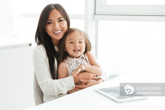 Happy smiling asian mom holding her little daughter