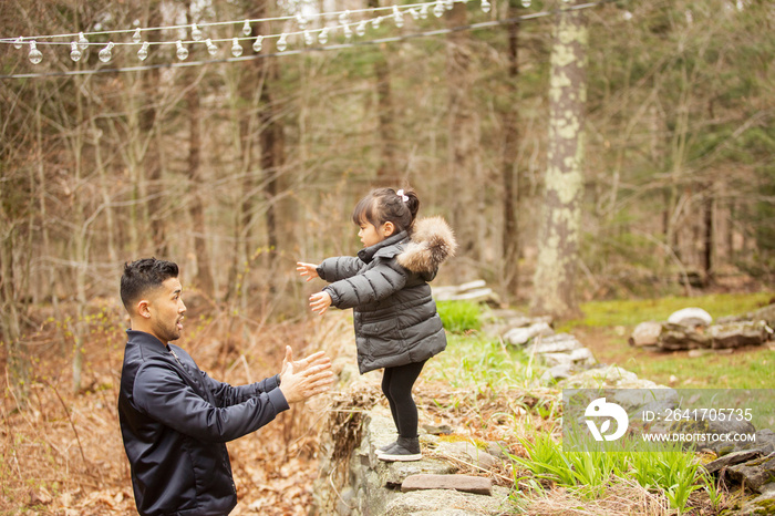 Daughter jumping into fathers arms in forest