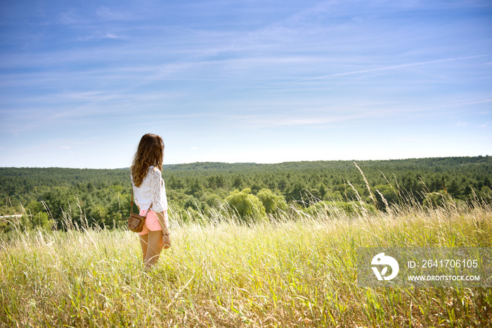 Woman standing in meadow looking at view