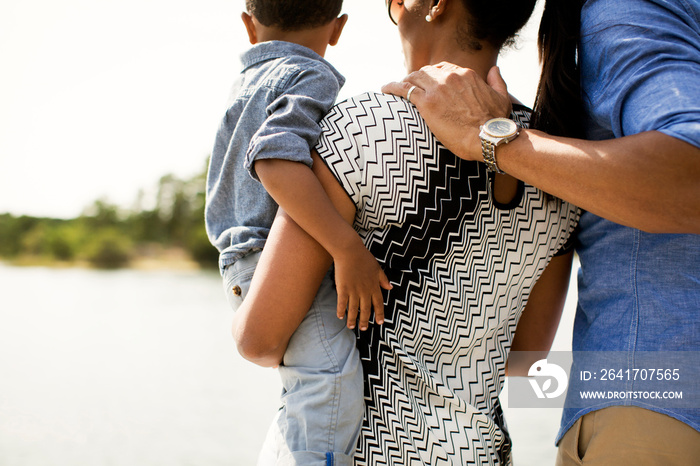 Boy (18-23 months) looking at river with his parents