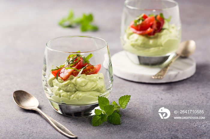 Fresh green avocado mousse with cherry tomatoes in glasses. Healthy vegan food concept with copy spa