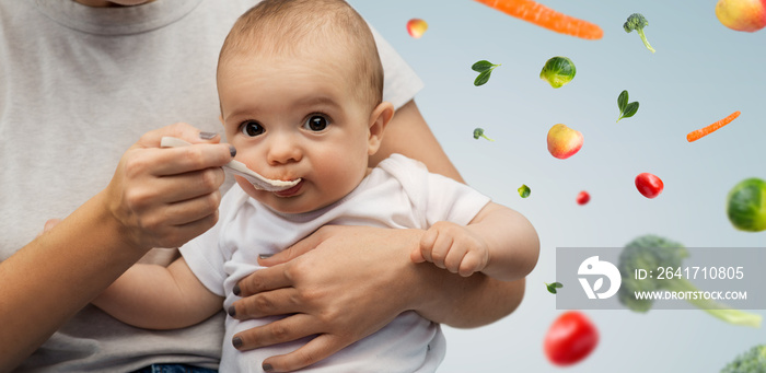 child, eating and food concept - close up of mother with spoon feeding little baby over fruits and v