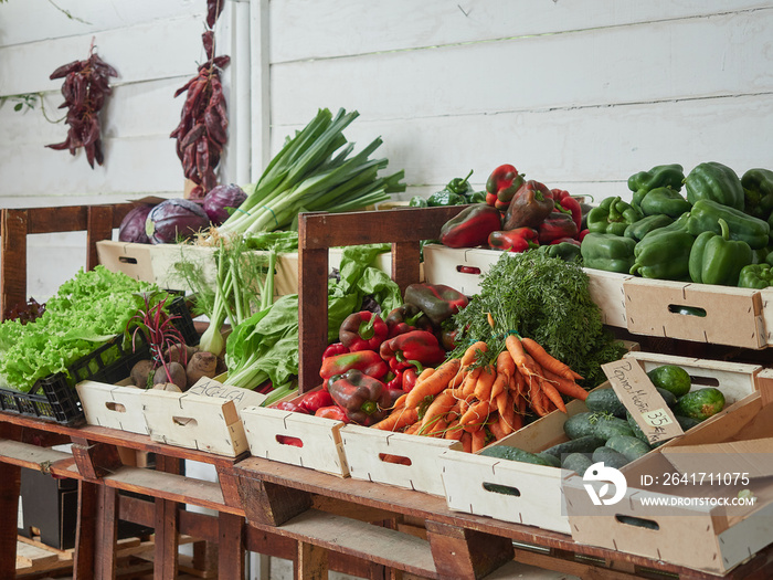 variety of fresh organic vegetables in wooden crates for sale at the farmers market. Carrots, peppe