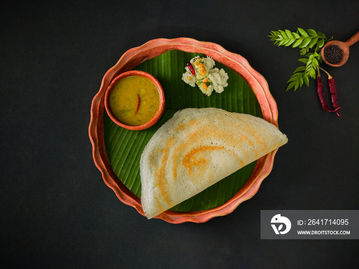 traditional south indian food masala dosa, sambar and coconut chutney served on clay plate and banan