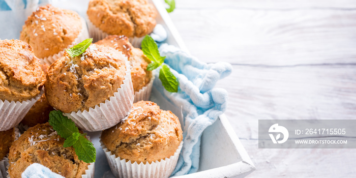 Delicious homemade coconut cinnamon muffins and mint leafs on old white tray. Healthy food concept w