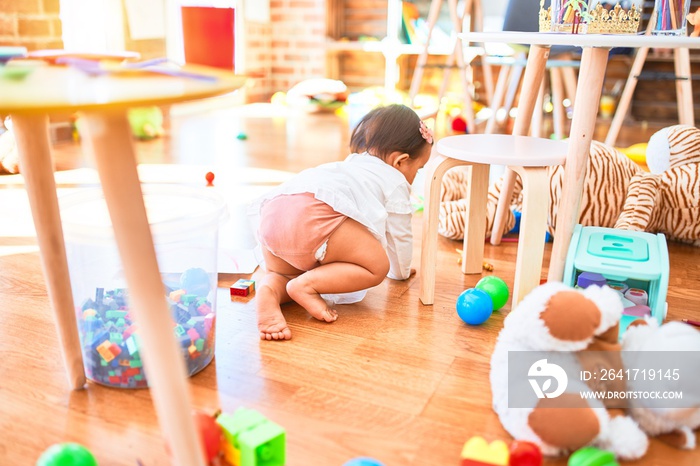 Beautiful infant happy at kindergarten around colorful toys