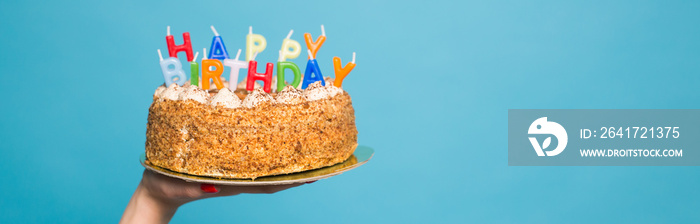 手拿着一个有蜡烛的生日蛋糕，蓝色背景上写着生日。复制S