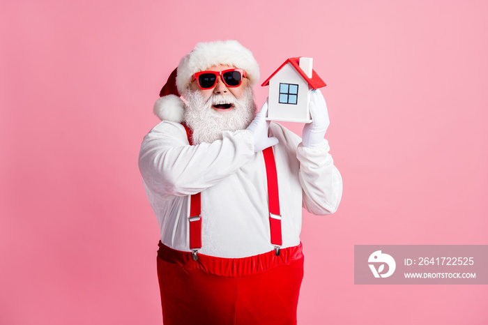 Portrait of his he nice attractive cheerful cheery glad fat Santa holding in hands house property in