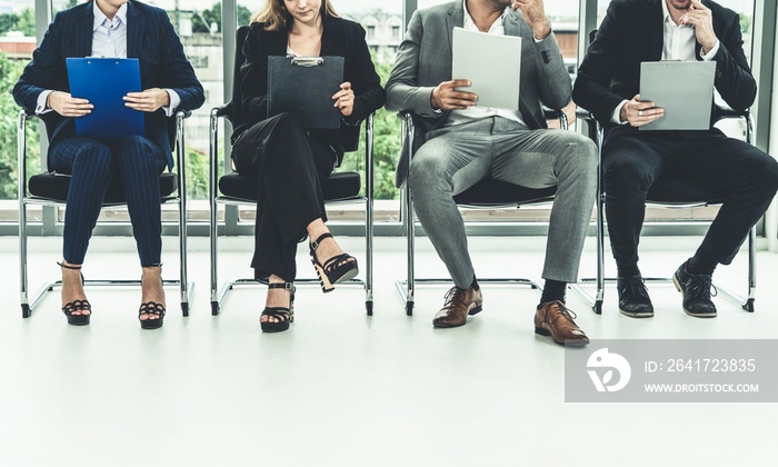 Businesswomen and businessmen holding resume CV folder while waiting on chairs in office for job int